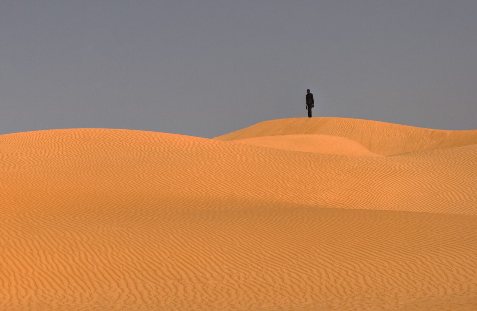 Silhouette of a man atop Maimalari Dunes, Yobe State, Northeast Nigeria, at sunset.