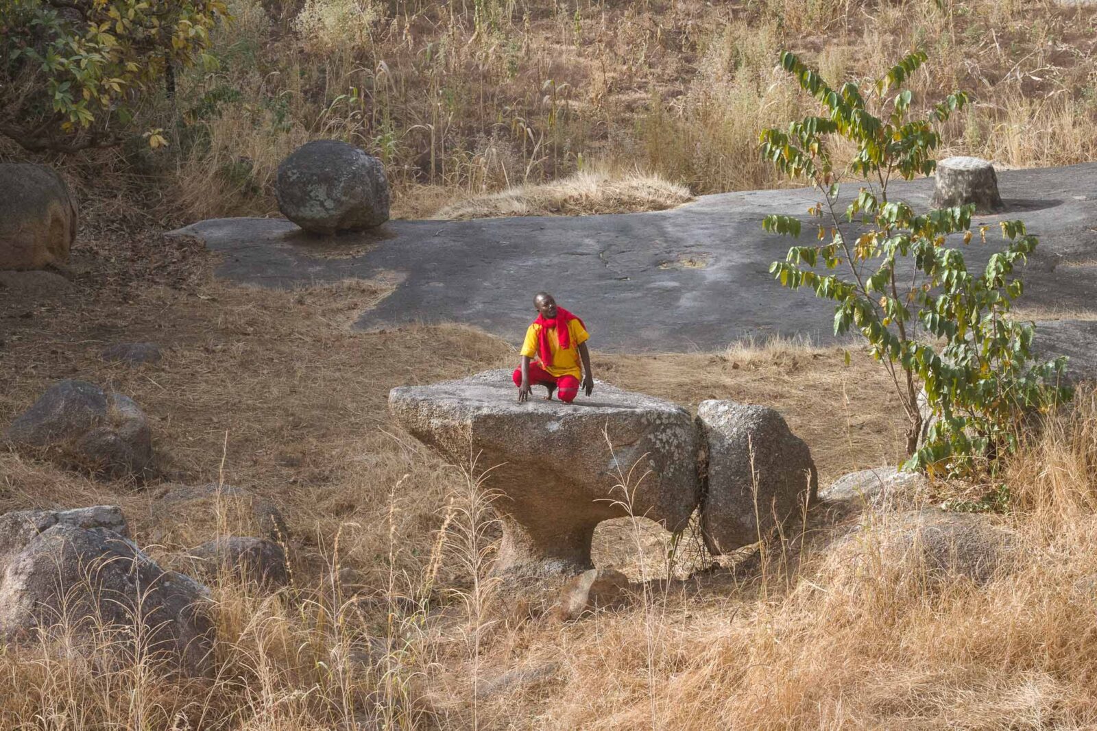 Kagoro’s Footprints Stool-shaped stone used for games with pebbles in Kagoro, Southern Kaduna, surrounded by rocks and dried grass.