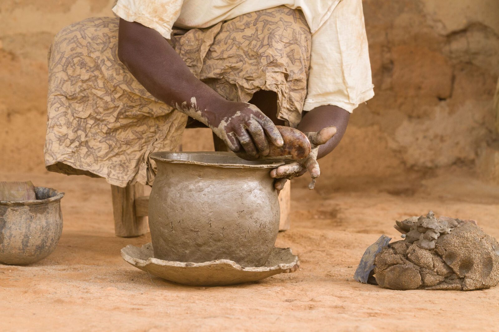 Close-up of hands shaping a clay pot—Attakar pottery-making process, Southern Kaduna, Nigeria.