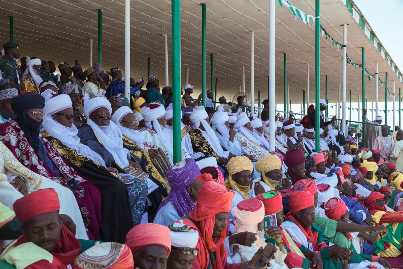 Argungu Fishing Festival Traditional rulers from across Nigeria seated in the auditorium, with traditional guards in front, watching the Argungu Fishing Festival.